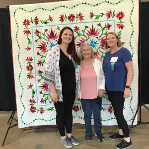 Congratulations to Raffle Quilt Winner, Remigia Williams, who is the mother of our guild member, Denise Price and grandmother of guild member Mindi Price who say that she is, “thrilled with the quilt!